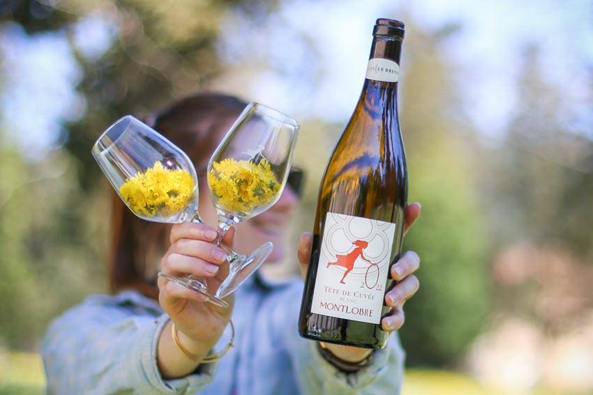 Zwei Gläser mit Blüten und eine Flasche Weißwein von Montlobre