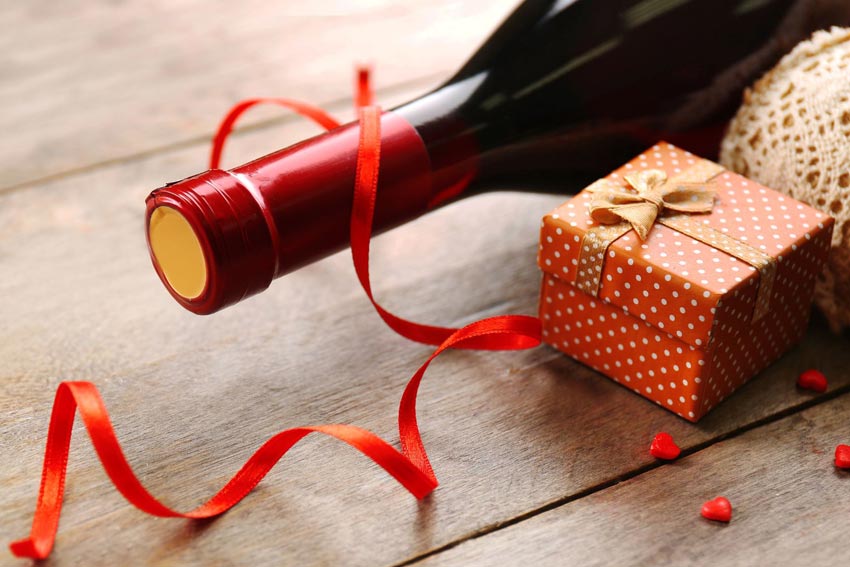 eine Falsche Wein auf einem Holztisch und ein kleines Päkchen daneben