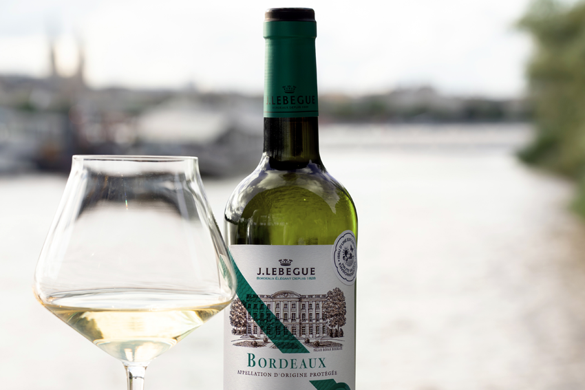 Eine Flasche weißer Bordeauxwein von Lebegue daneben ein Glas Weißwein