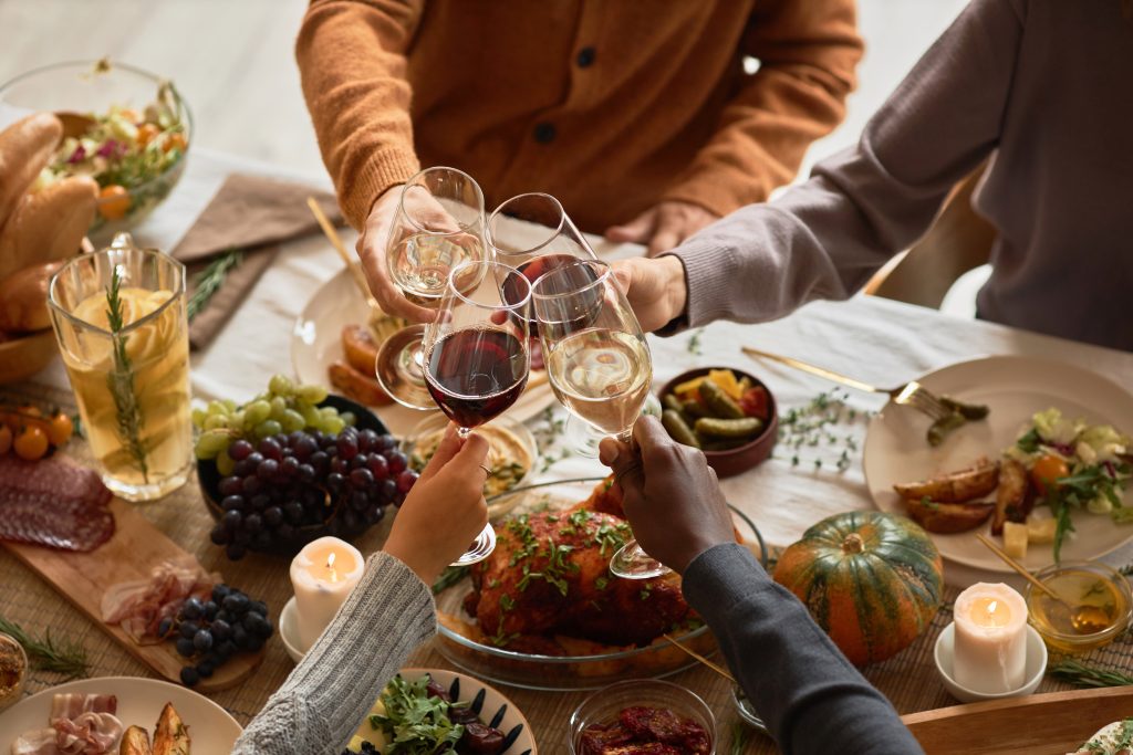 Menschen an einem Esstisch, die mit einem Glas Wein anstoßen